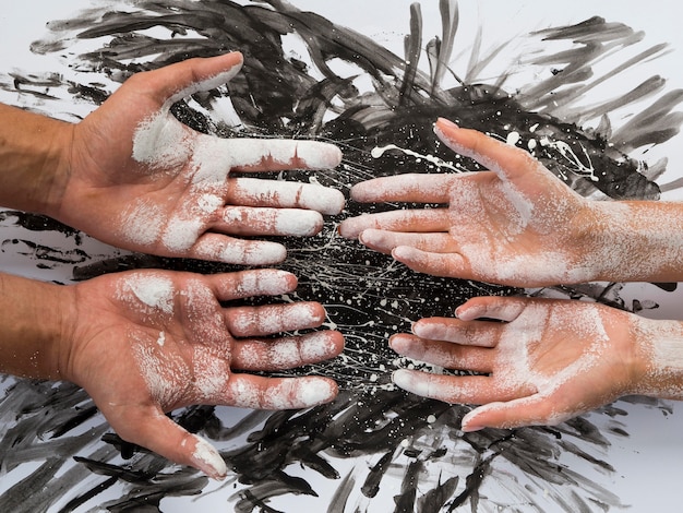 Vue de dessus de la paire de mains recouvertes de peinture blanche