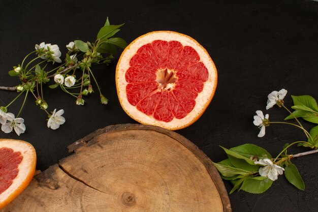 Vue de dessus de pamplemousse en tranches avec fleur blanche sur le sol sombre