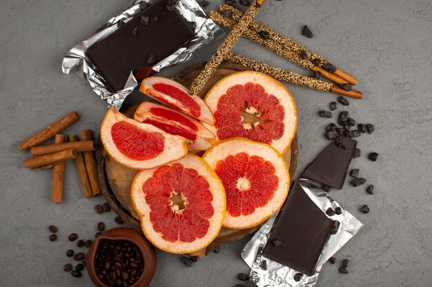 Vue de dessus de pamplemousses en tranches de cannelle et de chocolat sur le bureau gris