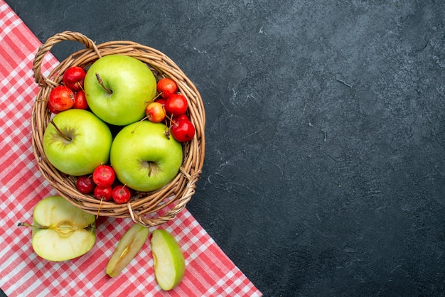 Vue de dessus panier avec fruits pommes et cerises douces sur fond gris foncé fruits berry composition fraîcheur plante d'arbre