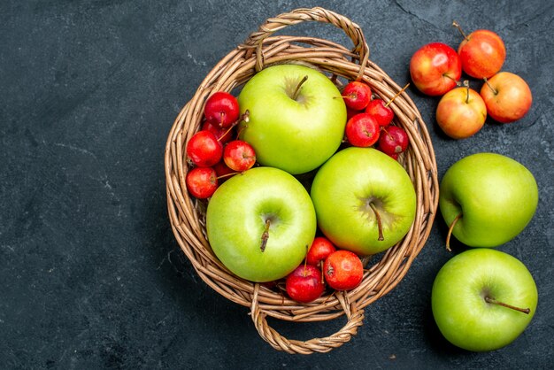 Vue de dessus panier avec fruits pommes vertes et cerises douces sur la composition de fruits de surface gris foncé arbre fraîcheur douce