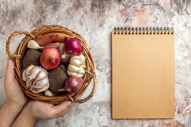 Vue de dessus panier avec légumes ails oignons et betteraves avec bloc-notes sur photo légère couleur de régime de salade mûre