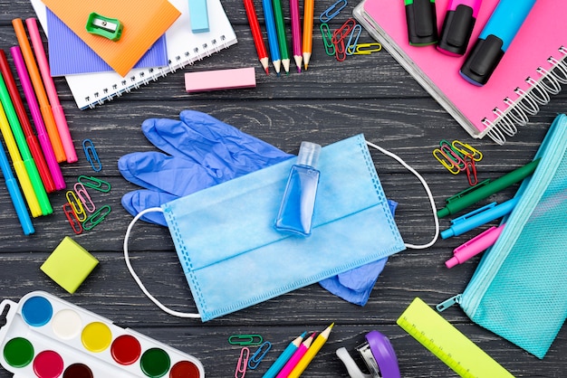 Vue de dessus de la papeterie de retour à l'école avec masque médical et crayons multicolores