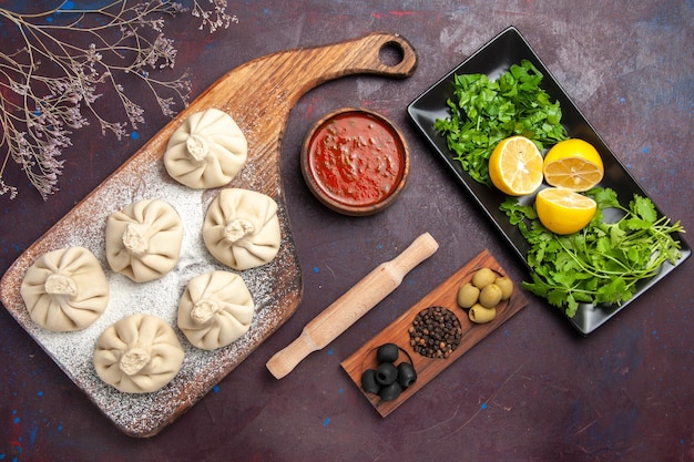 Vue de dessus de la pâte de boulettes crues avec sauce tomate et citron sur fond noir