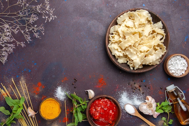 Vue De Dessus De La Pâte Crue En Tranches Avec Des Assaisonnements Sur Un Fond Sombre De La Pâte De Pâtes Alimentaires Repas Dîner