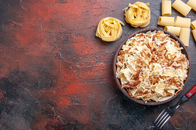 Vue de dessus de la pâte cuite en tranches avec du riz sur la pâte de pâtes repas plat surface sombre