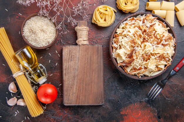 Vue de dessus de la pâte cuite en tranches avec du riz sur la pâte de plat de pâtes surface sombre foncé