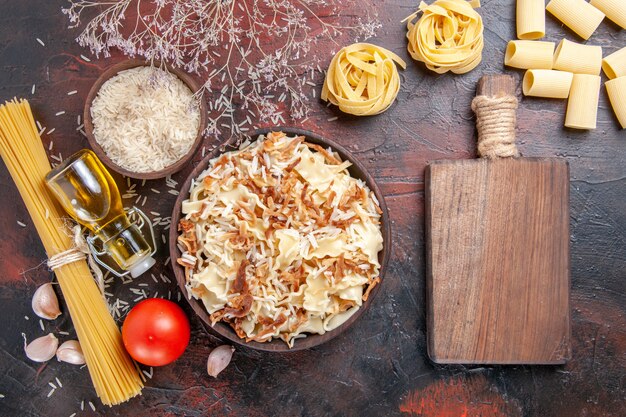 Vue de dessus de la pâte cuite en tranches avec du riz sur la pâte de plat de pâtes surface sombre foncé