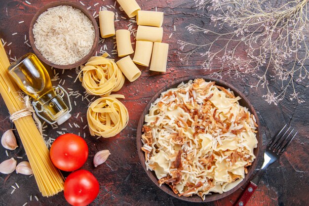 Vue de dessus de la pâte cuite en tranches avec du riz sur un plat de pâtes de bureau foncé pâte sombre