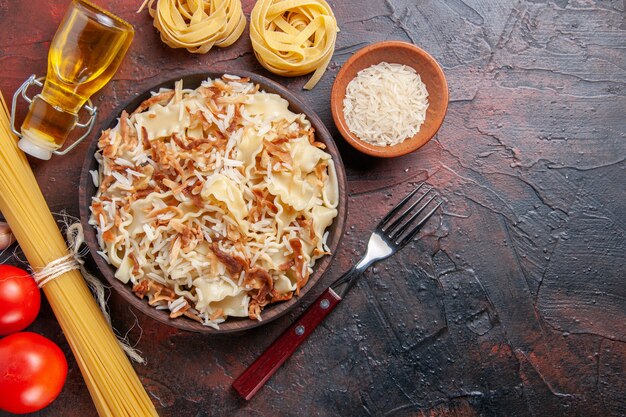 Vue de dessus de la pâte cuite en tranches avec du riz sur une surface sombre pâte de plat de pâtes foncées