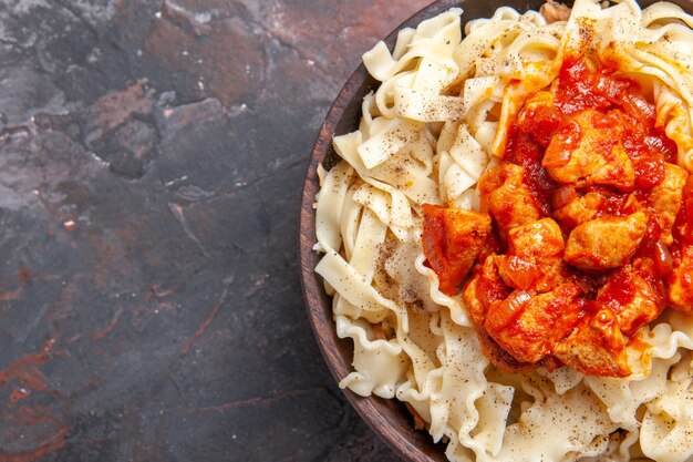 Vue de dessus de la pâte cuite avec des tranches de poulet et de la sauce sur un plat noir de pâte de pâtes