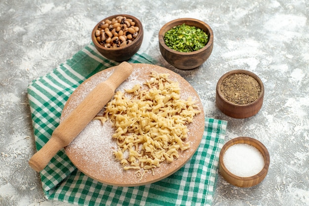 Vue de dessus de la pâte et du rouleau à pâtisserie sur un plateau de pâte sur une nappe sur fond gris