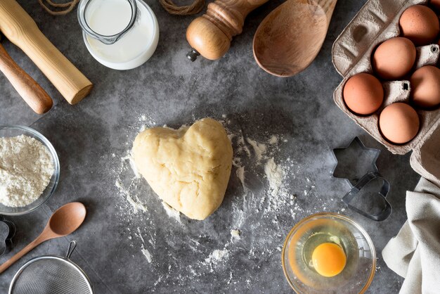 Vue de dessus de la pâte en forme de coeur sur le comptoir avec de la farine et des œufs