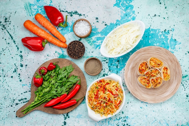 Vue de dessus de la pâte de légumes en tranches avec une garniture savoureuse avec des carottes vertes et des poivrons rouges épicés sur la collation de repas de petit pain de bureau bleu vif