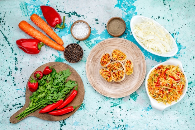 Vue de dessus de la pâte de légumes en tranches avec une garniture savoureuse avec salade de carottes vertes et poivrons rouges épicés sur le bureau bleu vif