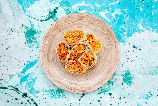 Vue de dessus de la pâte de petits pains de légumes en tranches avec garniture sur la table bleu vif collation photo couleur légumes rouleau