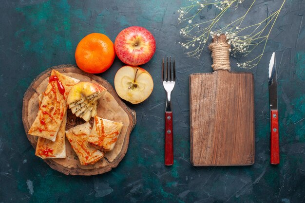 Vue de dessus de la pâte pita roulée en tranches avec sauce et fruits sur le bureau bleu foncé