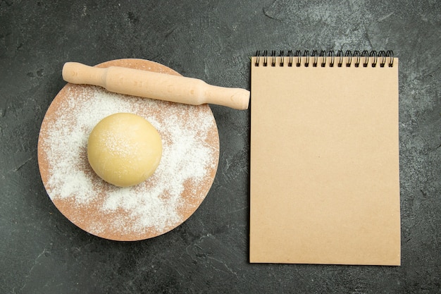 Vue de dessus de la pâte ronde crue avec de la farine sur le fond gris pâte farine de repas cru alimentaire