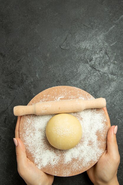 Vue de dessus de la pâte ronde crue avec de la farine sur la pâte de bureau gris farine de repas cru alimentaire