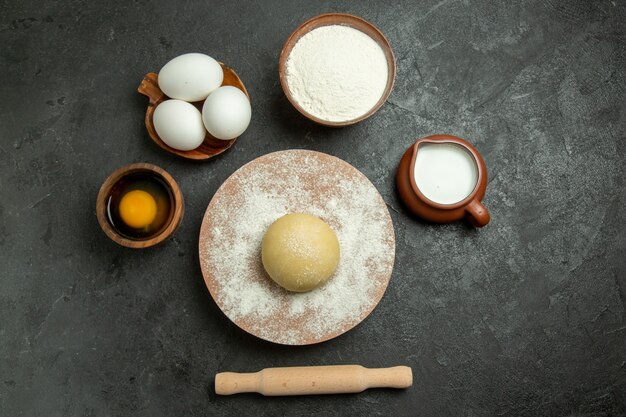 Vue de dessus pâte ronde crue avec des œufs et de la farine sur fond gris farine de repas de pâte alimentaire