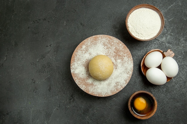 Vue de dessus de la pâte ronde crue avec des œufs et de la farine sur fond gris repas de pâte alimentaire farine crue