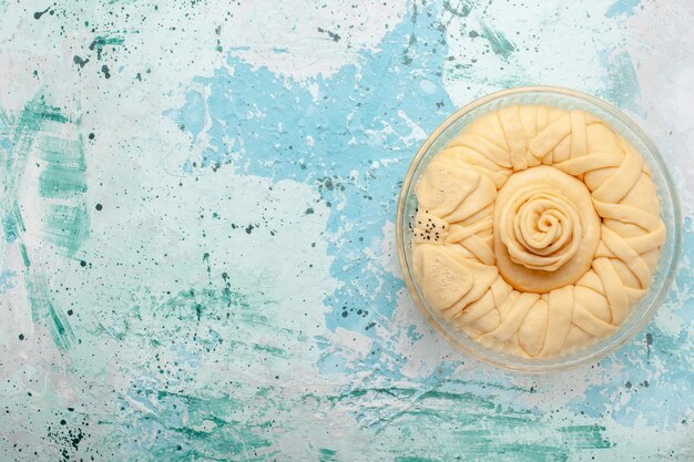 Vue de dessus de la pâte à tarte crue ronde formée sur le bureau bleu