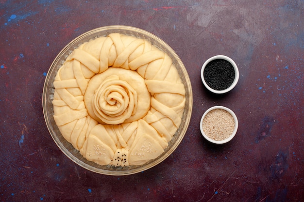 Photo gratuite vue de dessus de la pâte à tarte crue ronde formée sur un bureau violet foncé