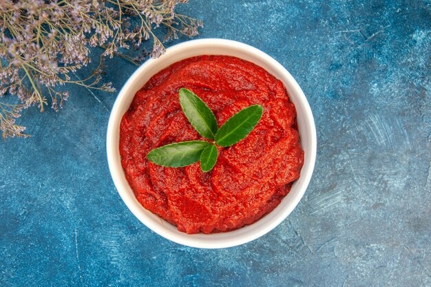 Vue de dessus de la pâte de tomate fraîche sur une table bleue