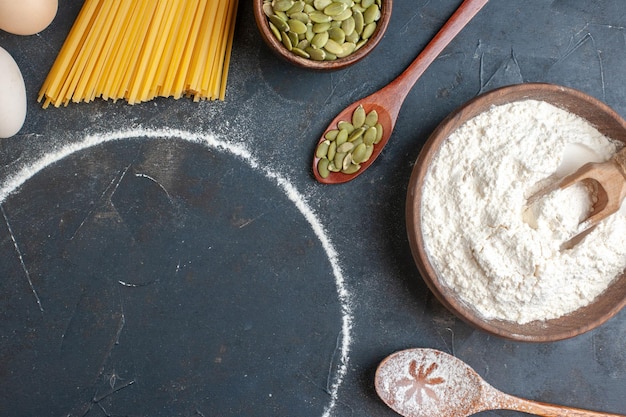 Vue de dessus pâtes crues avec céréales et œufs sur fond sombre pâte alimentaire couleur photo obscurité cuisine de cuisson