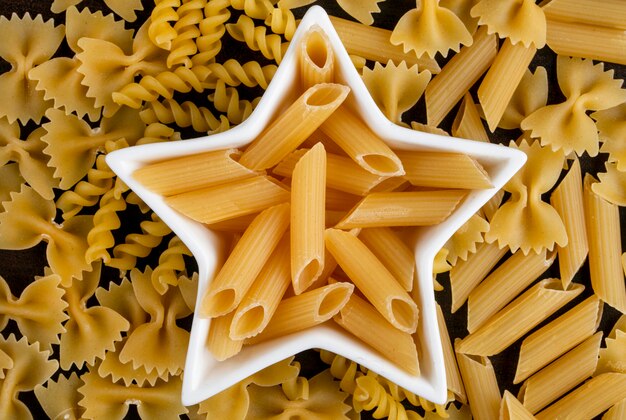 Vue de dessus des pâtes crues dans une rosace en forme d'étoile avec des spaghettis sur une surface en bois