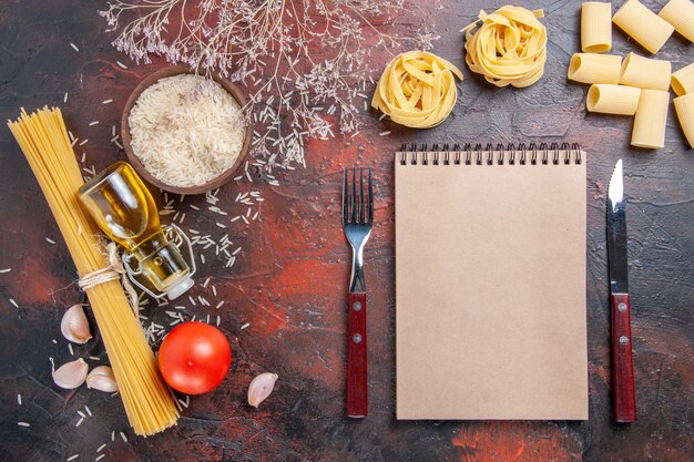 Vue de dessus des pâtes crues avec du riz sur des pâtes de pâte de surface sombre crues