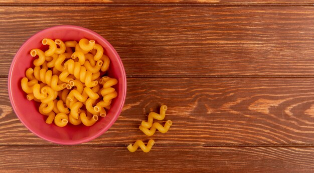 Vue de dessus des pâtes fusilli dans un bol sur une surface en bois avec espace copie