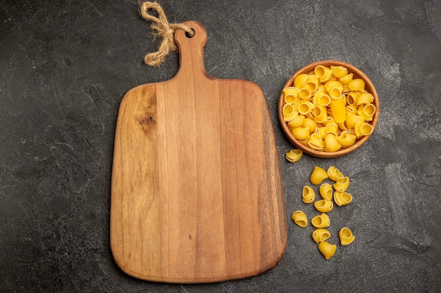 Photo gratuite vue de dessus des pâtes italiennes crues à l'intérieur des assiettes brunes sur un bureau gris