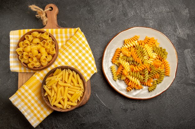 Vue de dessus des pâtes italiennes crues à l'intérieur des assiettes brunes sur le gris