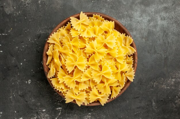 Vue de dessus des pâtes italiennes crues à l'intérieur de la plaque sur fond gris foncé