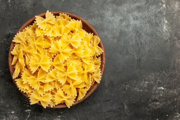 Vue de dessus des pâtes italiennes crues à l'intérieur de la plaque sur fond gris foncé