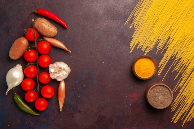 Vue de dessus des pâtes italiennes crues avec des légumes frais et des assaisonnements sur des pâtes repas de bureau sombre couleur alimentaire pâte Italie