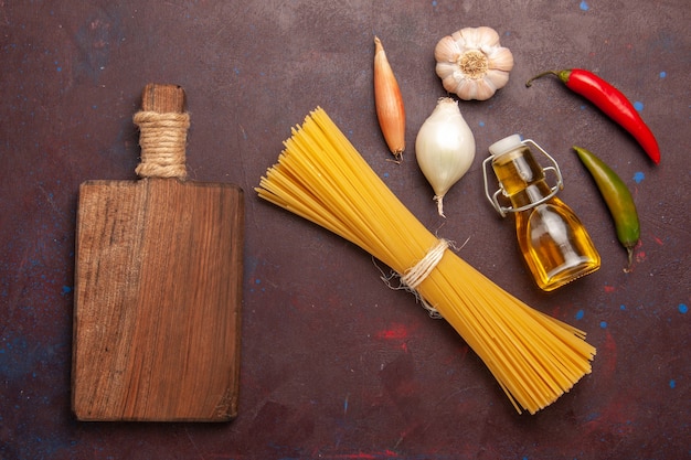 Vue de dessus pâtes italiennes crues longtemps formées sur fond violet foncé repas pâte alimentaire pâtes légumes crus