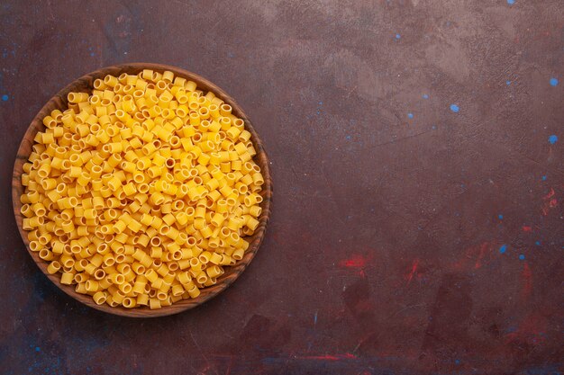 Vue de dessus pâtes italiennes crues peu formé à l'intérieur de la plaque sur fond sombre pâte alimentaire repas de pâtes beaucoup