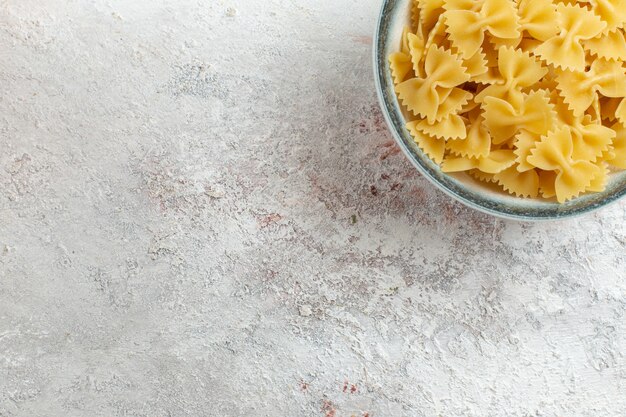 Vue de dessus pâtes italiennes crues peu formées sur le fond blanc pâte de légumes alimentaire repas de pâtes italiennes