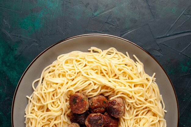 Vue de dessus des pâtes italiennes cuites avec des boulettes de viande sur le bureau bleu foncé