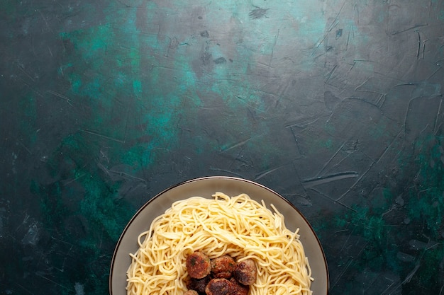 Vue de dessus des pâtes italiennes cuites avec des boulettes de viande sur la surface bleu foncé