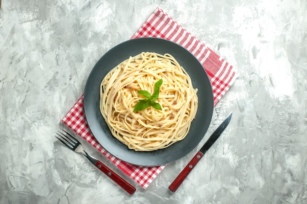 Vue de dessus des pâtes italiennes cuites avec des couverts sur fond blanc