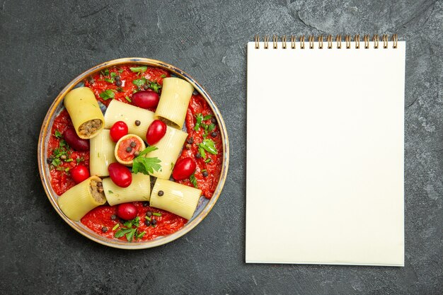 Vue de dessus des pâtes italiennes cuites délicieux repas avec de la viande et de la sauce tomate sur fond gris foncé pâte de pâtes sauce à la viande alimentaire