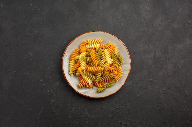 Vue de dessus des pâtes italiennes cuites pâtes en spirale inhabituelles à l'intérieur de la plaque sur l'espace sombre