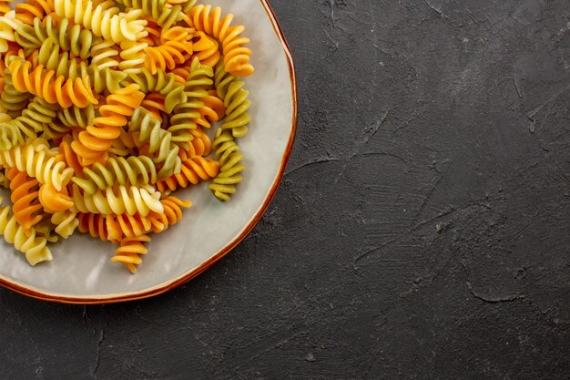 Vue de dessus des pâtes italiennes cuites pâtes en spirale inhabituelles à l'intérieur de la plaque sur l'espace sombre