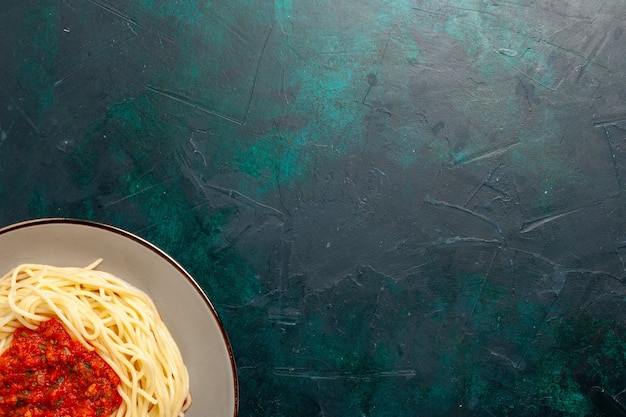 Photo gratuite vue de dessus pâtes italiennes cuites avec viande hachée et sauce tomate sur la surface bleu foncé