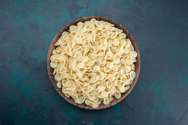 Vue de dessus des pâtes italiennes à l'intérieur de la plaque sur bleu foncé