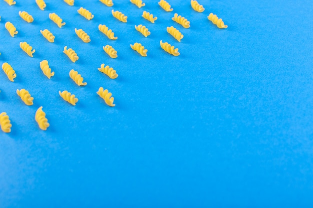 Une vue de dessus des pâtes jaunes brutes isolées doublées de pâtes italiennes sèches sur le fond bleu des repas spaghetti