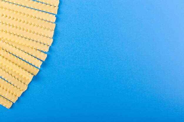 Une vue de dessus pâtes longues italiennes jaune cru bordée sur le bleu